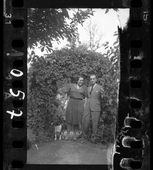 Couple with a dog standing under vine arch
