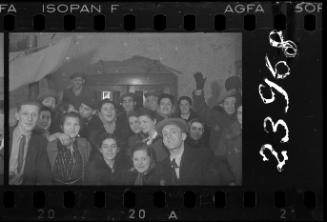 Large group of residents, wearing hats and coats, gathering in a home
