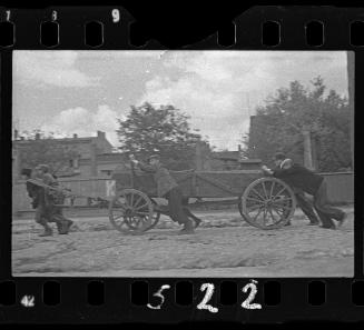 Boys pushing cart, probably a hearse