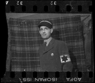 Portrait of a Jewish policeman standing in front of a plaid blanket