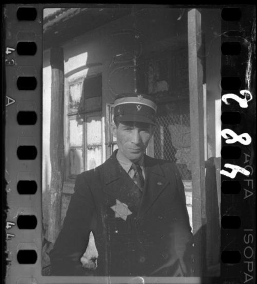 A Jewish policeman, standing outside an unidentified building in the ghetto