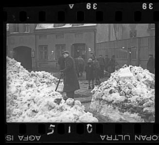 Man with shovel and other residents on the street in winter