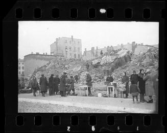 Residents selling wares outside the ruins of the synagogue on Wolborska Street, destroyed by the Germans in 1939