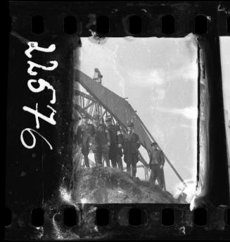 Four Jewish policemen and one unidentified man standing beside an unidentified structure