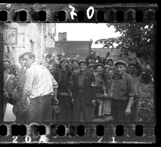 Jewish policemen standing in front of residents with arms raised