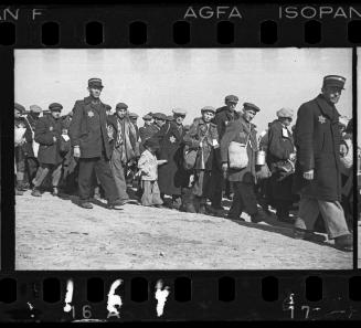 Deportation, people walking looking at camera, small boy in centre escorted by ghetto police