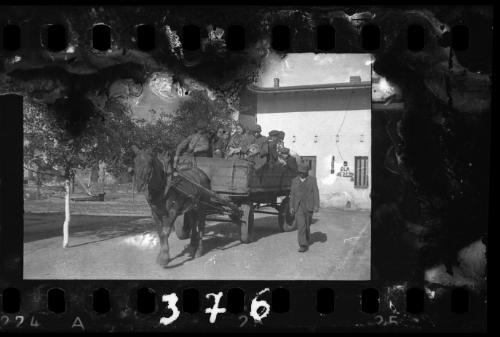 Man walking alongside horse-drawn deportation wagon carrying residents being deported from the ghetto