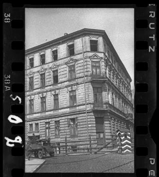Four-storey building on street corner with wooden fence