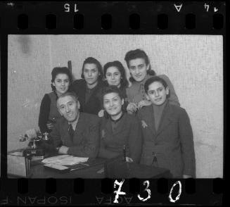 Group of Jewish men and women posing around a desk