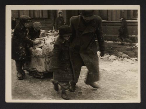 Man and boys moving cart with bread