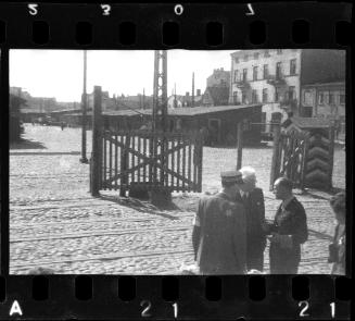 Chaim Rumkowksi, a Jewish policeman and an unidentified man (possibly a German official or a member of the Judenrat) beside an entry gate to the ghetto
