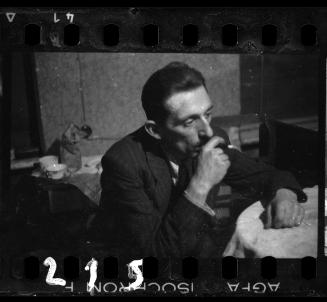 Portrait of Henryk Ross sitting at a table, smoking a cigarette