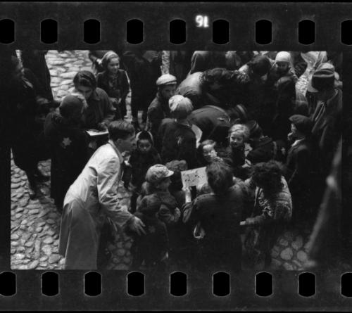 Postal workers distributing mail to a crowd of residents in the ghetto