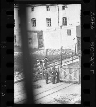 Two Jewish policemen beside an entry gate to the ghetto