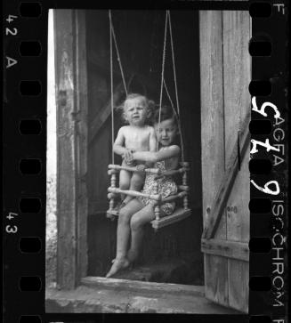 A girl and a boy in a doorway swing