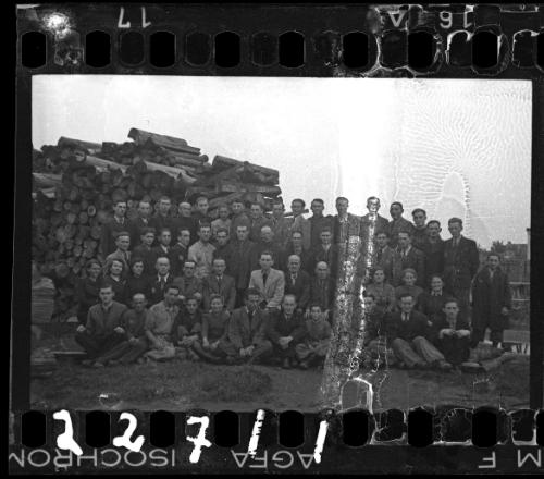 Large group portrait of members of the administration beside a stack of lumber