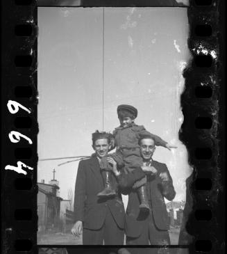 Two men holding a young boy on their shoulders