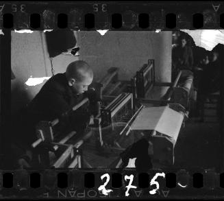 Young boy weaving on a loom in a workshop