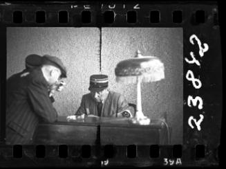 A Jewish policeman sitting at a desk, with another policeman and an unidentified man