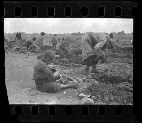 Young boy holding a pail while residents dig for food, coal and other provisions