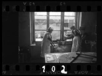 Cook ladling soup into pail to residents at window