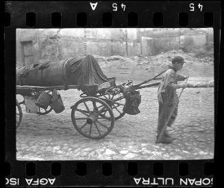 A fecal worker hauling a sewage collecting tank mounted on a wagon through the ghetto