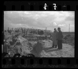 A German official overseeing workers digging trenches
