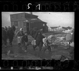 Boy walking to deportation in a group (wearing cap, satchel and backpack), winter
