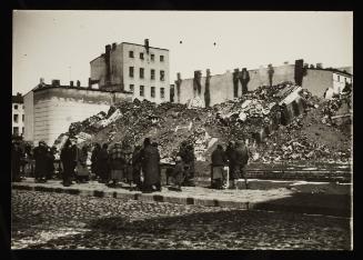 Small group of residents standing on street next to the ruins of the synagogue on Wolborska Street, destroyed by the Germans in 1939