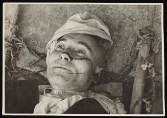 Body for burial - Older man with fabric cap, two beams tied with rope on either side