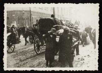 Workers moving cart through snow covered street