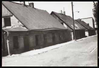 Empty road and wooden houses with chimneys