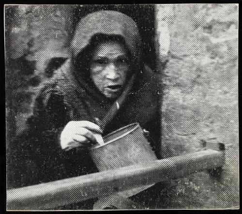 Starved old woman eating from a pail