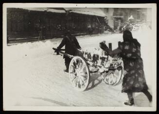 Two people moving cart with snow