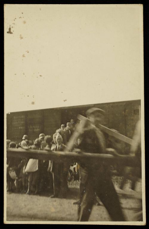 Residents boarding deportation train at Radogoszcz Station, man with lumber in the foreground