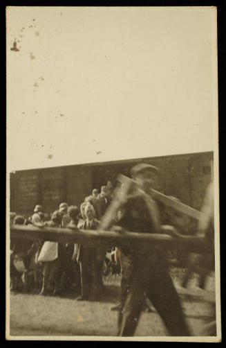 Residents boarding deportation train at Radogoszcz Station, man with lumber in the foreground