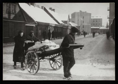 Three people moving cart with snow
