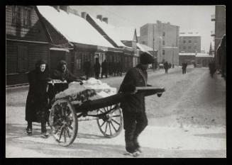 Three people moving cart with snow