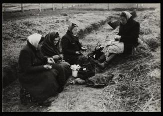 Women sitting in a field and peeling potatoes