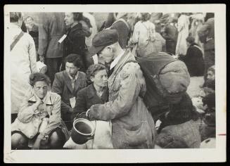 Old man carrying pail with sack on back, in deportation crowd