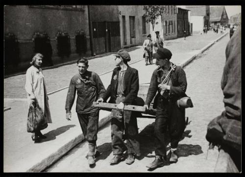 Three boys pulling cart along street