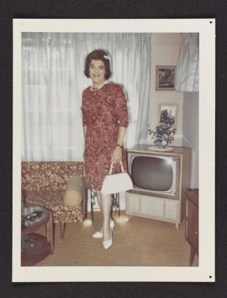 [Unnamed crossdresser in front of the television in a pink patterned dress, location unknown]
