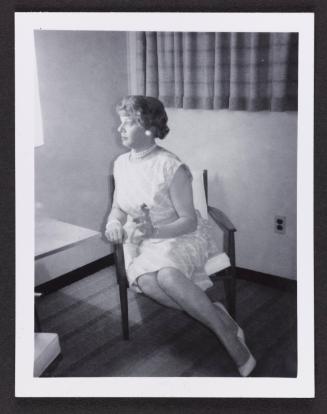 [Blond Anita sitting on an armchair in an hotel room, location unknown]
