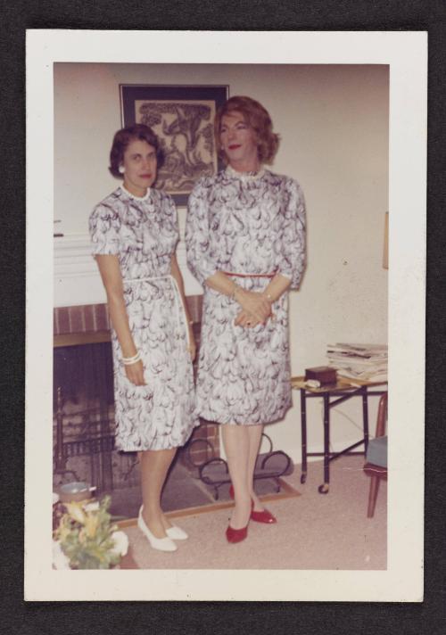 [Sheila with her wife, Avi, standing by the fireplace in matching dresses, Casa Susanna, Hunter, NY]
