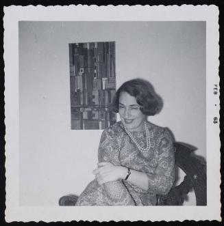 [Brunette in a paisley dress posing in front of a painting, location unknown]
