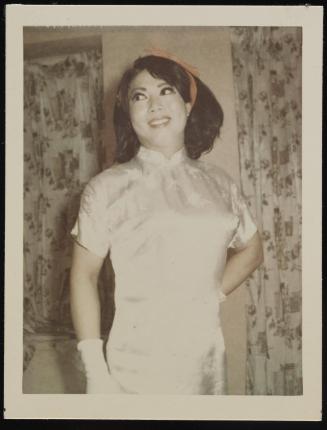 [Lili with a red ribbon in her hair, wearing a white silk dress, location unknown]
