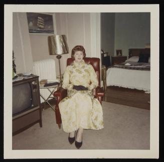 [In a gold and cream brocade dress, location unknown]
