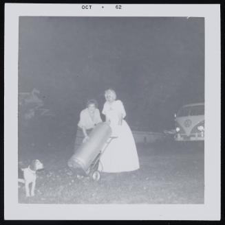 [Two ladies in long dresses with canister, location unknown]
